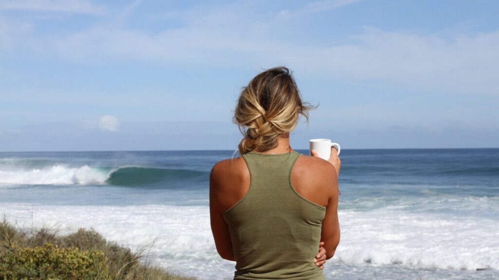 海辺でコーヒーを飲む女性